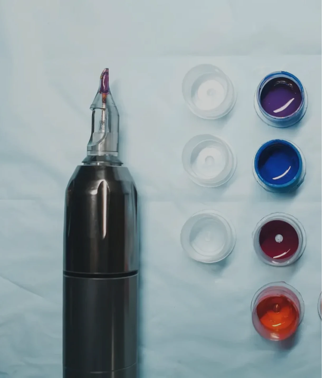 Tattoo machine and colorful ink cups.