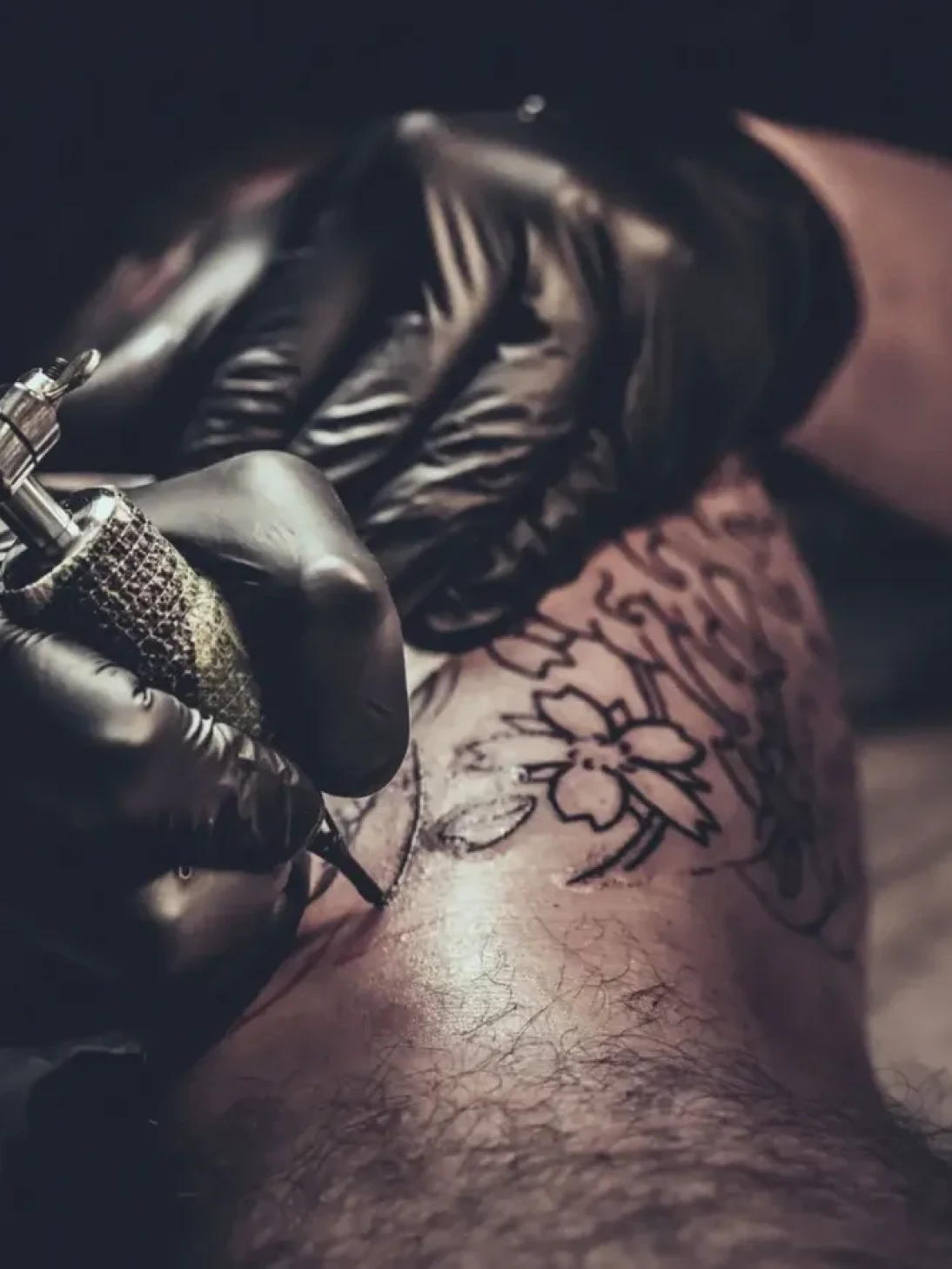 Tattoo artist inking floral design tattoo.